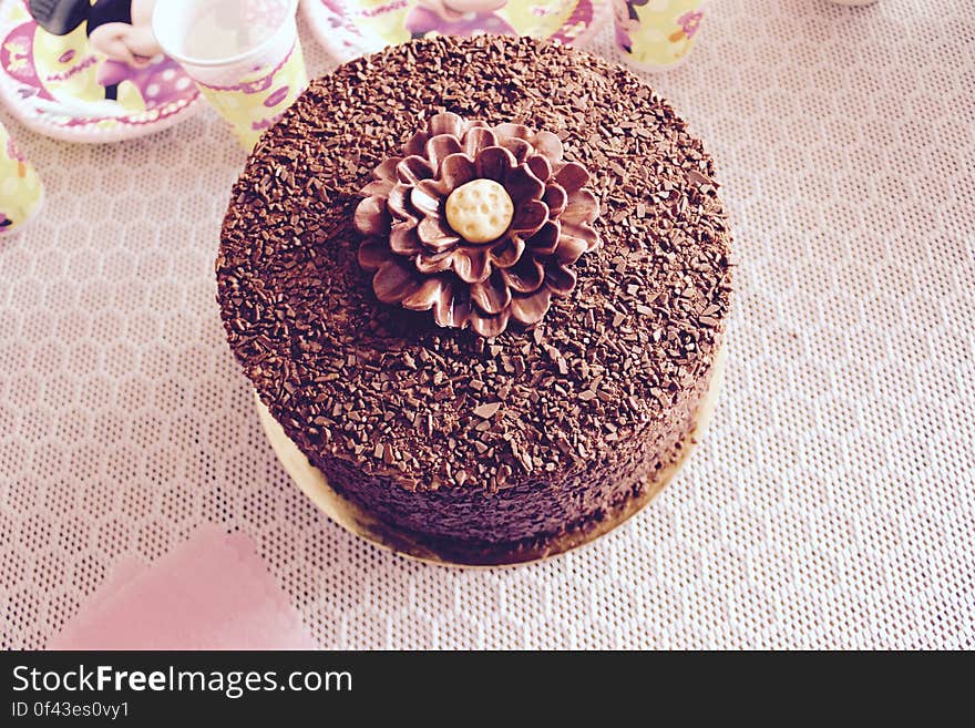 Overhead view of frosted and decorated chocolate cake on party table with paper plates and cups. Overhead view of frosted and decorated chocolate cake on party table with paper plates and cups.