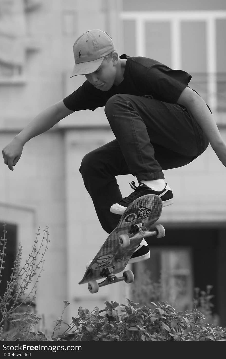 A black and white photo of a young man doing a skateboard jump.