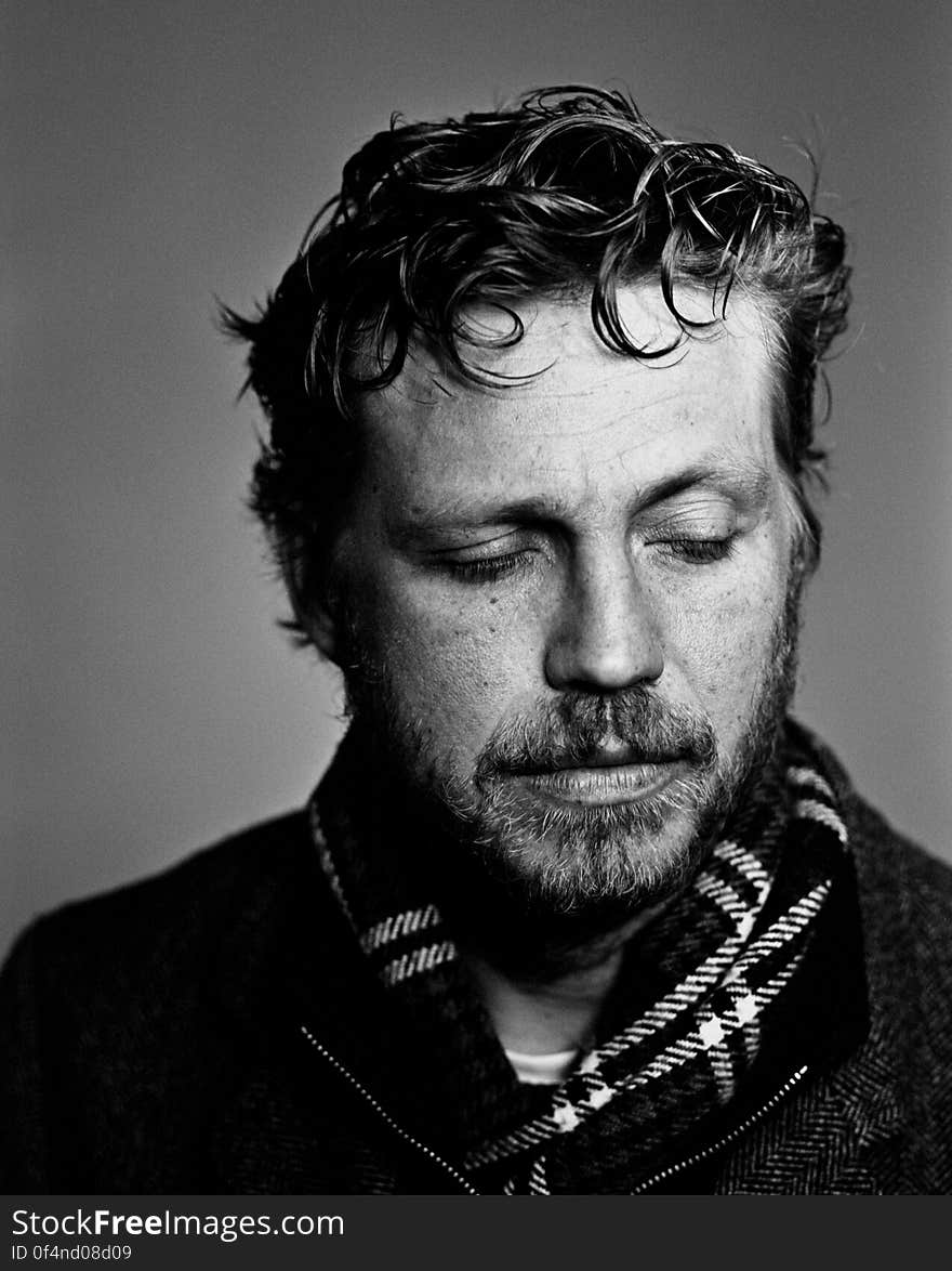 Black and white portrait of thoughtful young man with beard and scarf.