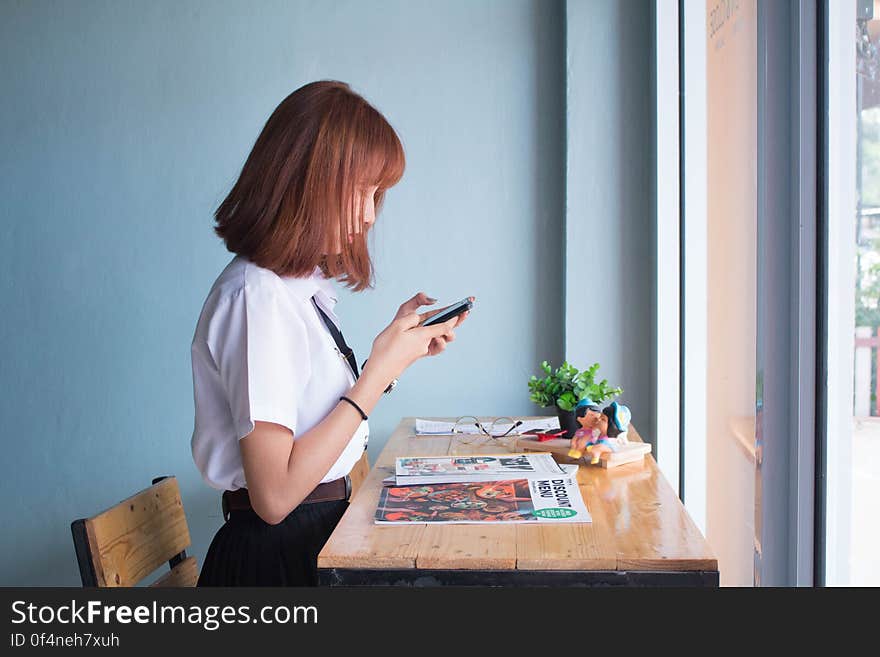 Girl sat at table at home using mobile phone. Girl sat at table at home using mobile phone.