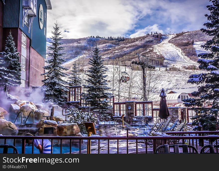 Exterior of resort with hot tub in snowy mountain landscape on sunny day. Exterior of resort with hot tub in snowy mountain landscape on sunny day.