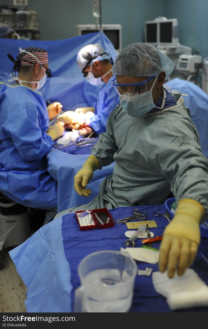 Surgeons around table in operating room during medical procedure. Surgeons around table in operating room during medical procedure.