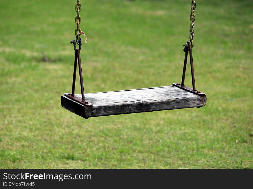 A wooden swing on the grass.