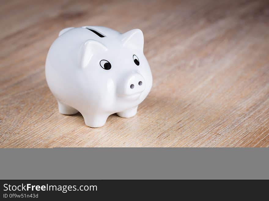 White Piggy Bank on Brown Wooden Surface