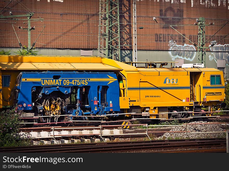 Railway locomotive engine in city, graffiti on brick building in background.