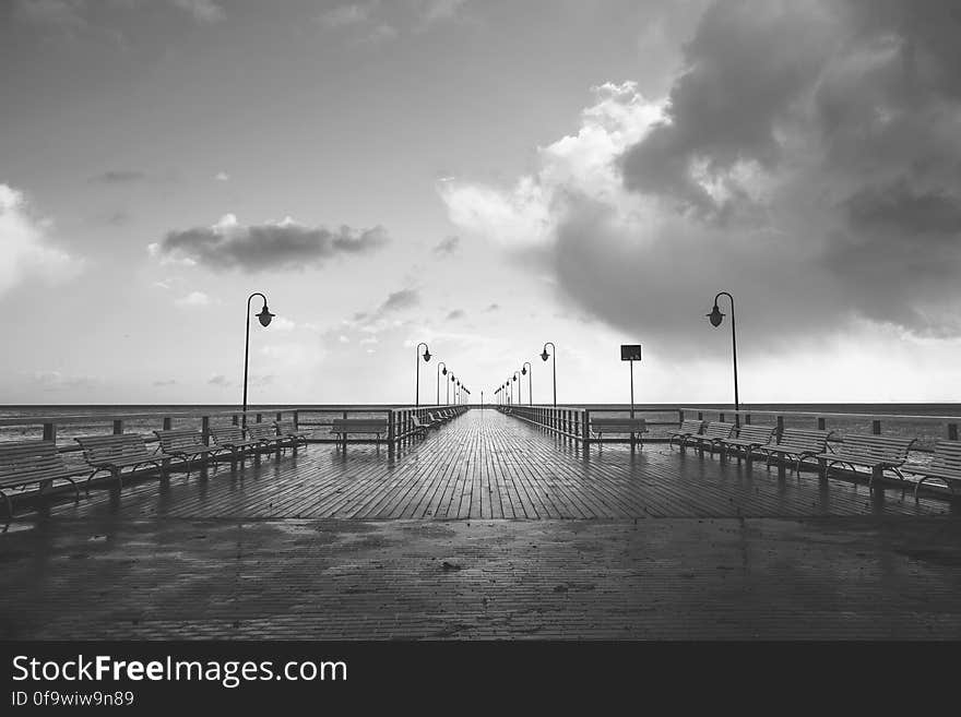 Wooden boardwalk and seaside pier in black and white.