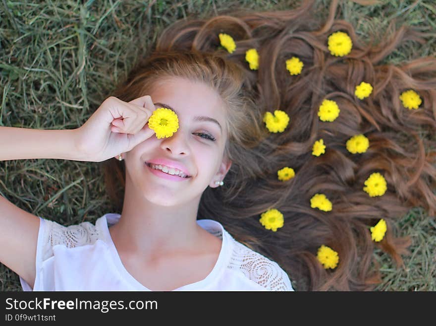 Portrait of teenage girl laying on ground with yellow flowers in long hair on green grass. Portrait of teenage girl laying on ground with yellow flowers in long hair on green grass.