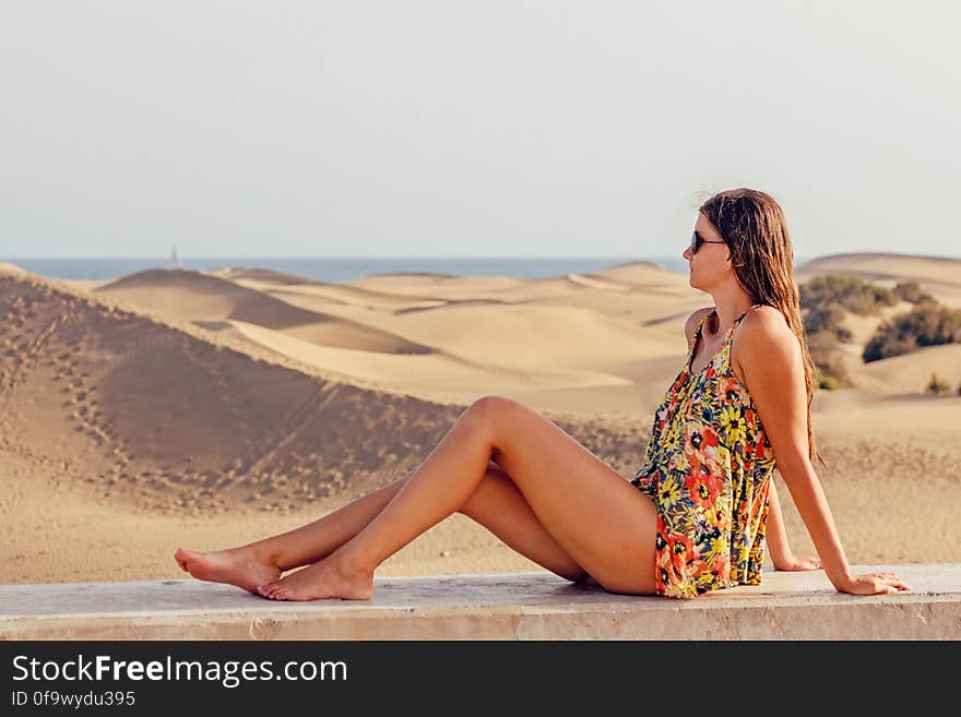 Woman Sitting on Sand at Beach Against Sky