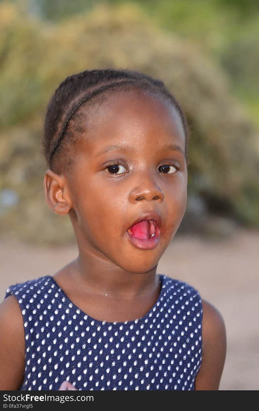 A close-up portrait of a young african girl looking at the camera with mouth wide open. A close-up portrait of a young african girl looking at the camera with mouth wide open