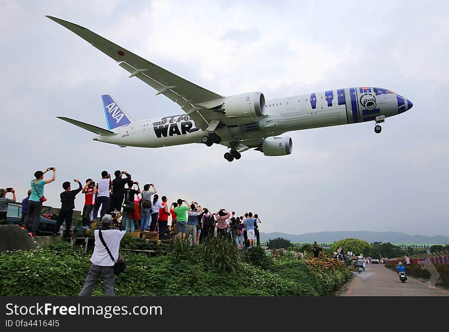 An All Nippon Airways plane with Star Wars design landing with spectators looking at it. An All Nippon Airways plane with Star Wars design landing with spectators looking at it.