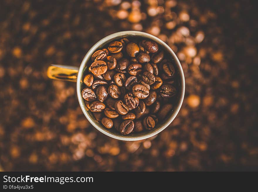 Overhead view of dry roasted beans in cup of coffee with textured brown background,. Overhead view of dry roasted beans in cup of coffee with textured brown background,