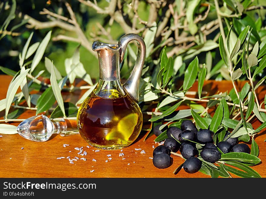 Stainless and Glass Swan Pitcher With Brown Liquid Besides Grapes and Glass Decanter Stopper during Daytime