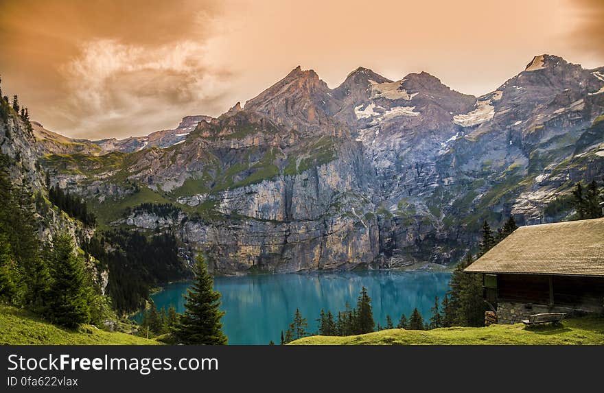 Exterior of rustic house on waterfront of alpine lake with orange skies. Exterior of rustic house on waterfront of alpine lake with orange skies.