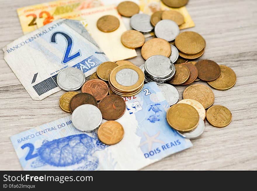 Close up of money notes and coins from Brazil on rustic wooden tabletop. Close up of money notes and coins from Brazil on rustic wooden tabletop.