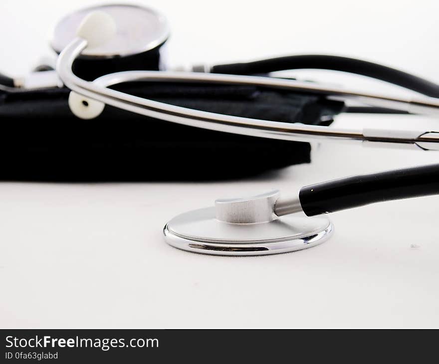 Stethoscope and blood pressure cuff on white studio background.