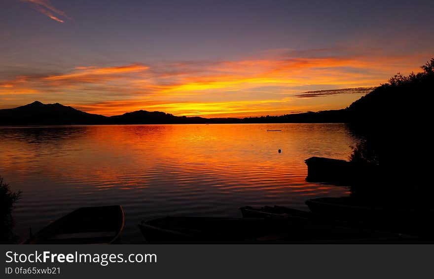 Sunset reflecting in lake along waterfront with clouds. Sunset reflecting in lake along waterfront with clouds.