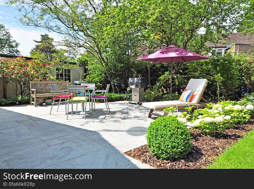 Summer garden furniture with sun-lounger and parasol in house garden. Summer garden furniture with sun-lounger and parasol in house garden.