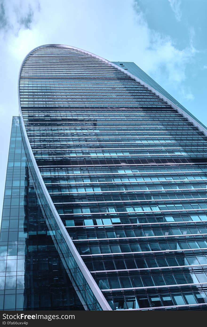 Low angle view looking to top of modern skyscraper with curved glass exterior. Low angle view looking to top of modern skyscraper with curved glass exterior.