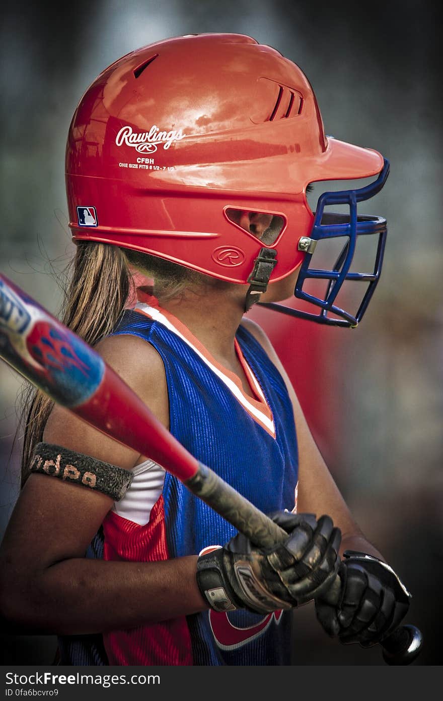 A portrait of a young girl with bat and helmet playing baseball. A portrait of a young girl with bat and helmet playing baseball.