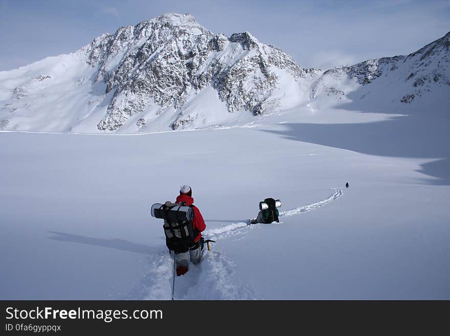 Hiker with backpack in snow in mountains on sunny day. Hiker with backpack in snow in mountains on sunny day.