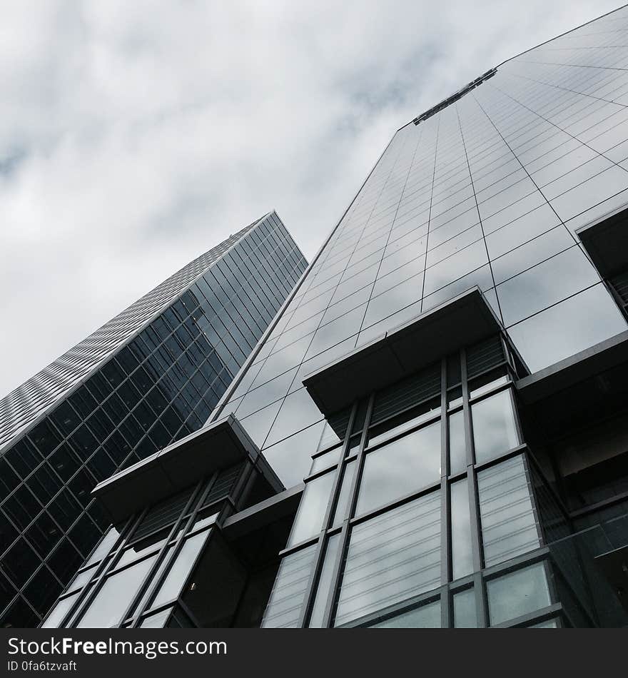 Upward view of ultramodern buildings constructed of glass and steel with two platforms for cleaning outside of one of the buildings. Upward view of ultramodern buildings constructed of glass and steel with two platforms for cleaning outside of one of the buildings.