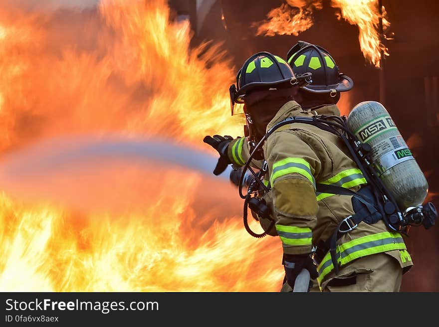 Two firemen putting out blazing fire. Two firemen putting out blazing fire.