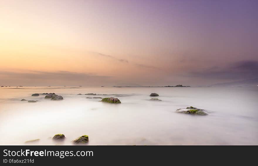 Scenic view of rocky landscape shrouded in fog at sunset.