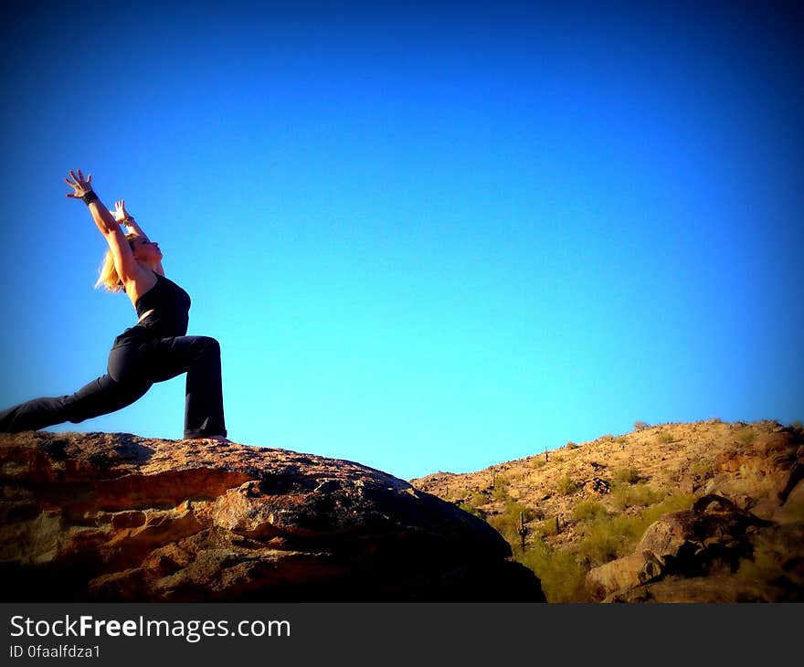 A woman outdoors doing yoga on a rock. A woman outdoors doing yoga on a rock.