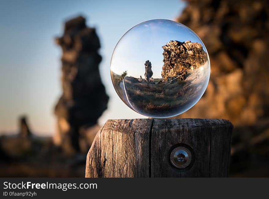 A sphere of glass on a wooden pole showing a focused image if a landscape. A sphere of glass on a wooden pole showing a focused image if a landscape.