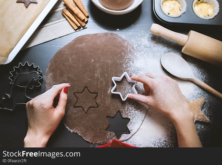 A person cutting ginger bread from piece of dough with a cookie cutter. A person cutting ginger bread from piece of dough with a cookie cutter.