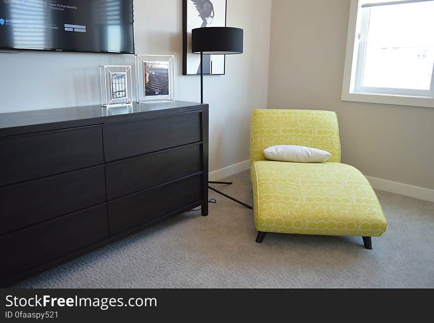 An room in an apartment with an yellow lounge chair in the corner.