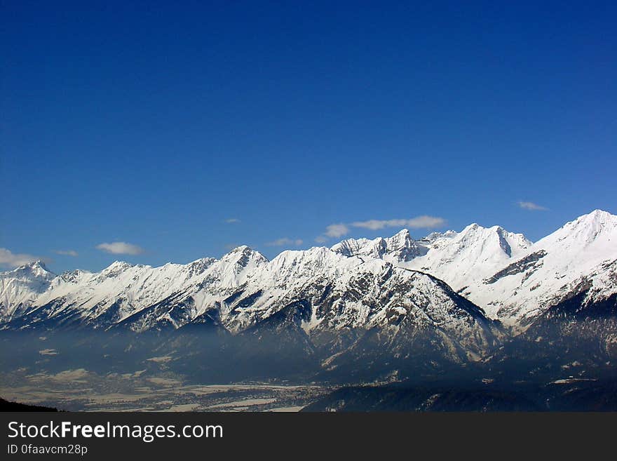 A snowy mountain range under blue skies.