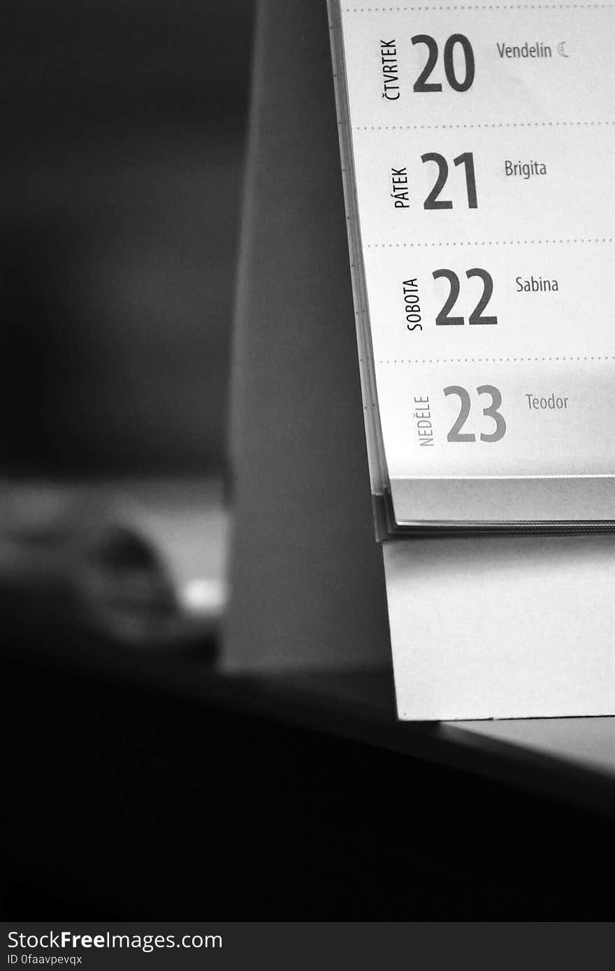 A black and white close up of a calendar on a desk. A black and white close up of a calendar on a desk.