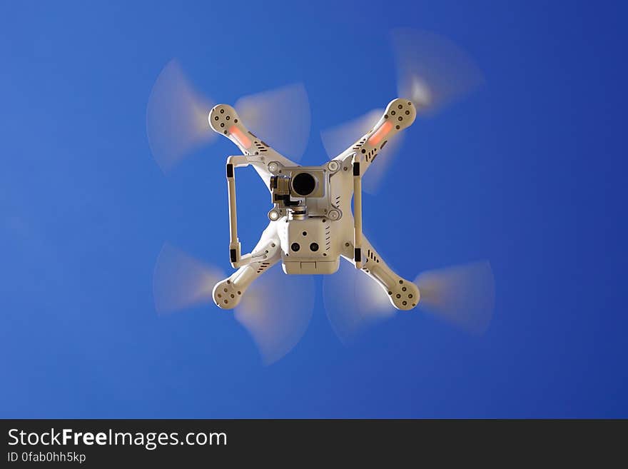 Drone flying overhead against blue skies on sunny day. Drone flying overhead against blue skies on sunny day.