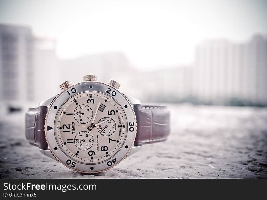 A close up of an elegant analog wrist watch on the ground.