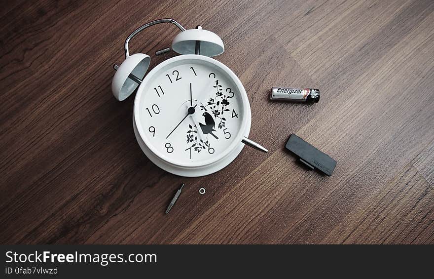 Alarm clock lying on wooden table with battery removed. Alarm clock lying on wooden table with battery removed.