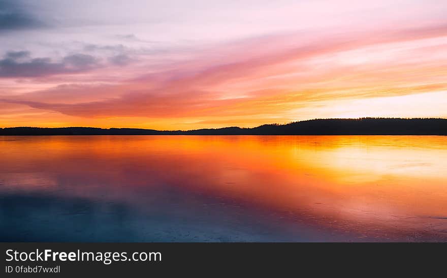 A sunset over a calm lake. A sunset over a calm lake.