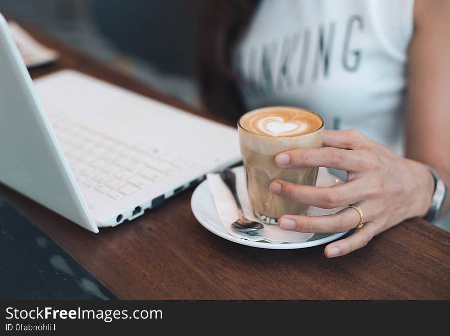 Close-up of Woman Holding Coffee Cup on Table