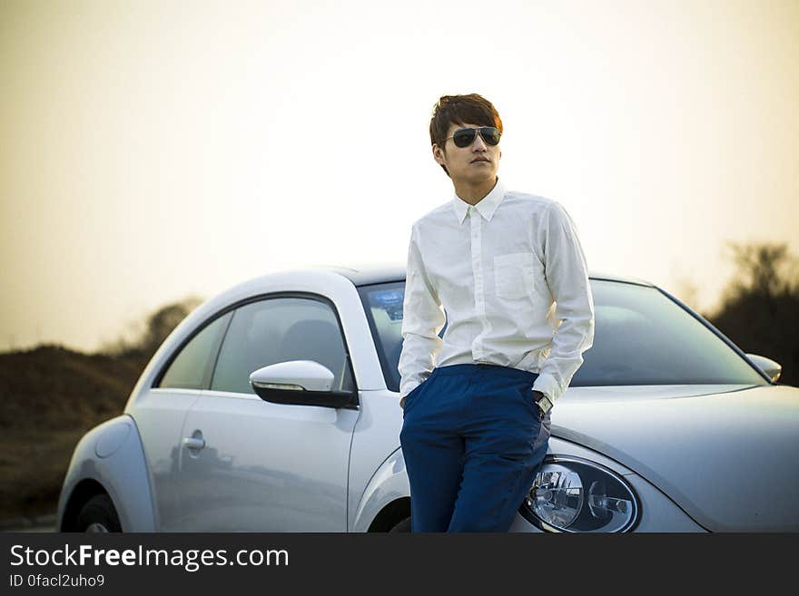 Man in White Button Down Shirt Leaning on Silver Beetle Car