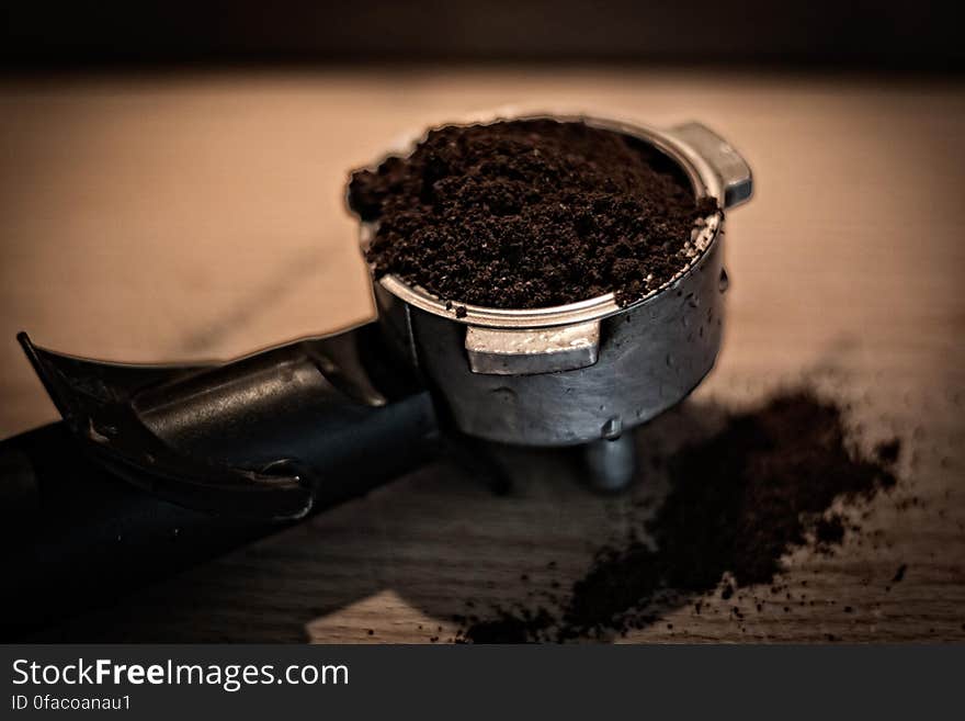 Close up of coffee grounds in espresso basket on wooden tabletop. Close up of coffee grounds in espresso basket on wooden tabletop.