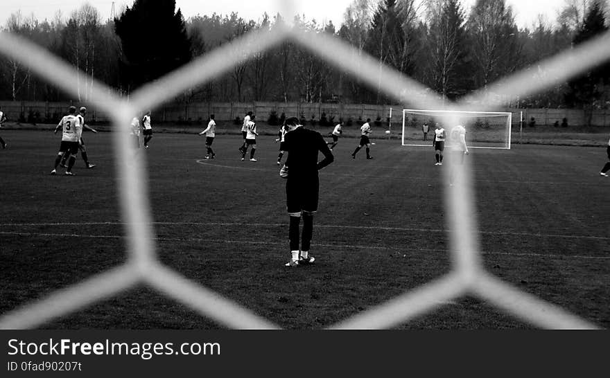 Players on soccer field through mesh net in black and white. Players on soccer field through mesh net in black and white.