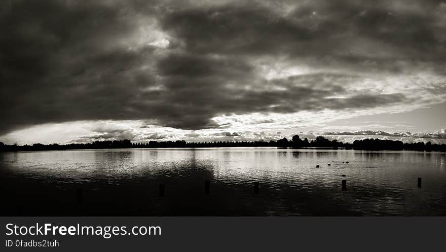 Sunset behind clouds over water in black and white. Sunset behind clouds over water in black and white.