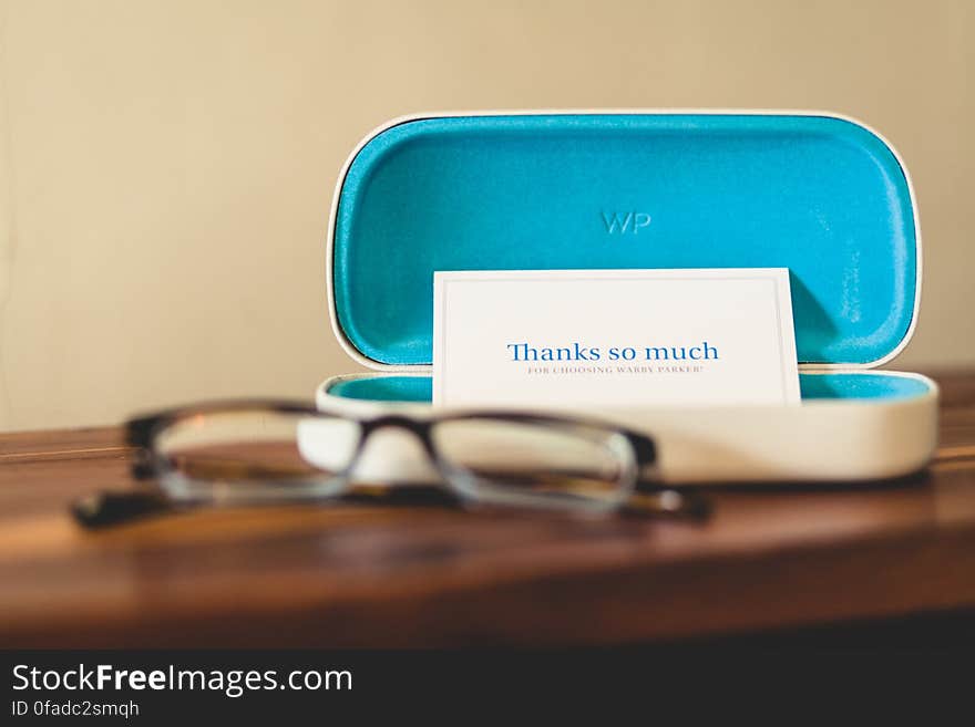 Eyeglasses on wooden table with open case holding thank you note. Eyeglasses on wooden table with open case holding thank you note.