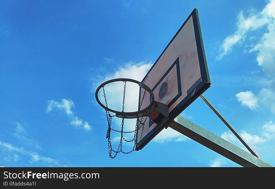 Low angle view of outdoor basketball backboard with blue sky and cloudscape background. Low angle view of outdoor basketball backboard with blue sky and cloudscape background.