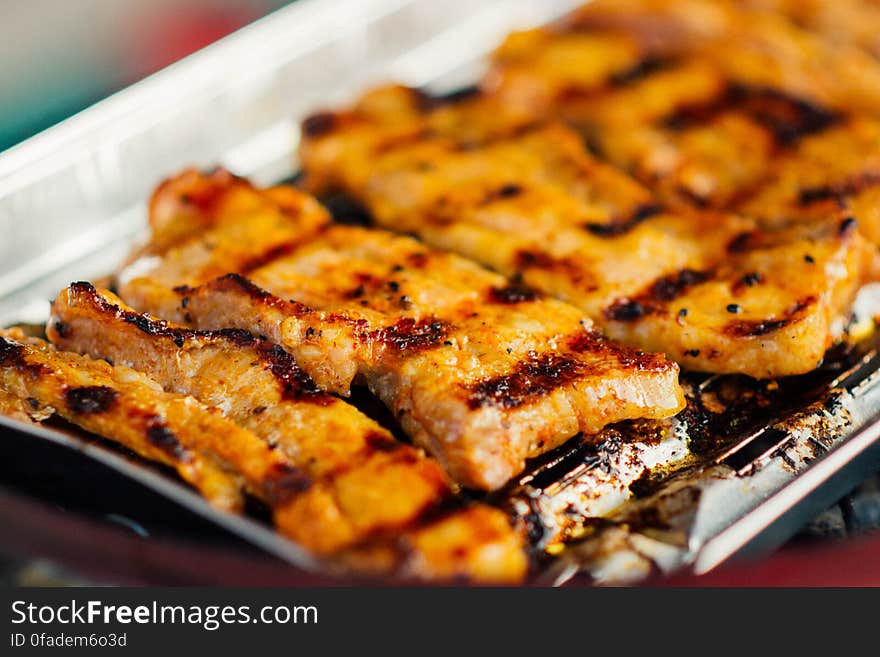 Close up of pieces of grilled pork on metal grate platter. Close up of pieces of grilled pork on metal grate platter.