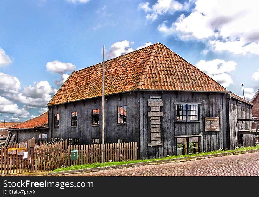 An old wooden cottage house with a wooden fence.