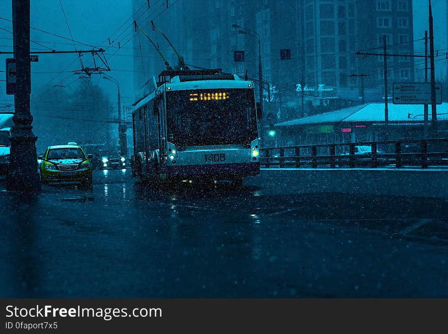 Tram on city streets with traffic in rain at night. Tram on city streets with traffic in rain at night.