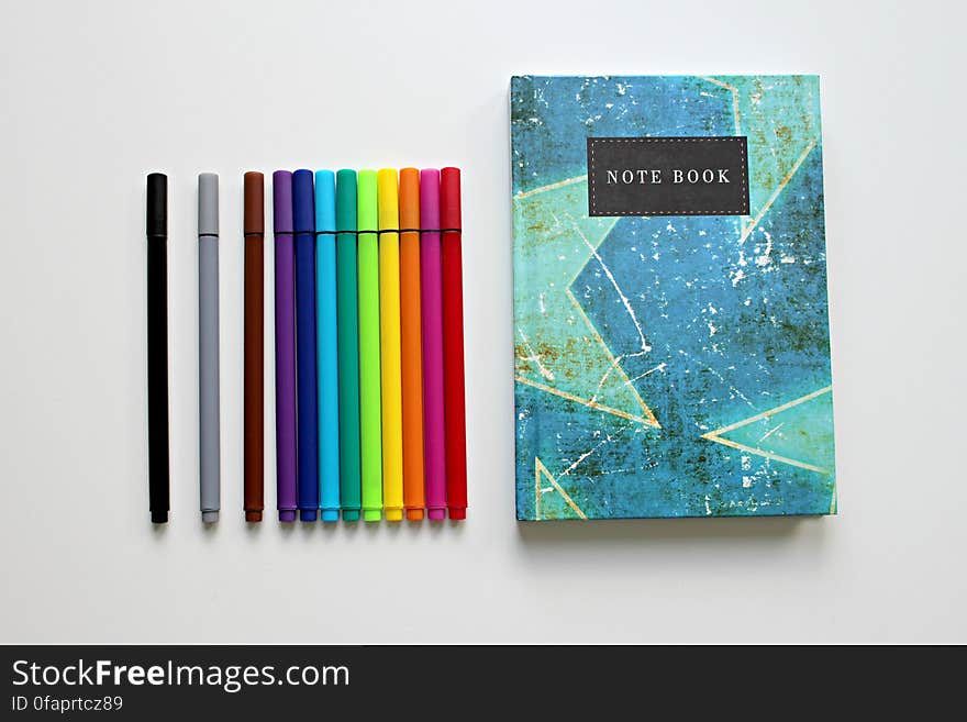 Colorful notebook with colored marker pens on white. Colorful notebook with colored marker pens on white.