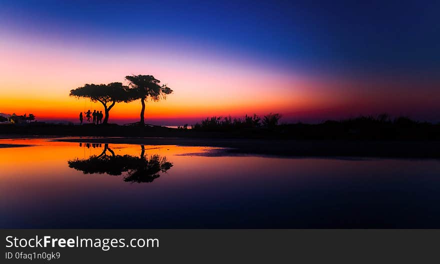 Silhouette of trees reflecting in calm waters in countryside at sunset. Silhouette of trees reflecting in calm waters in countryside at sunset.