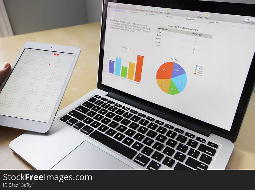 An opened laptop computer and a tablet with calendar and graph program. An opened laptop computer and a tablet with calendar and graph program.